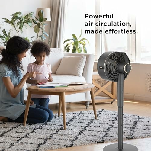 Mother and child drawing near a powerful air circulation fan in a living room.