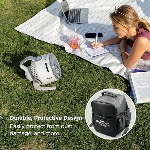 Woman studying outdoors with a portable fan and backpack.