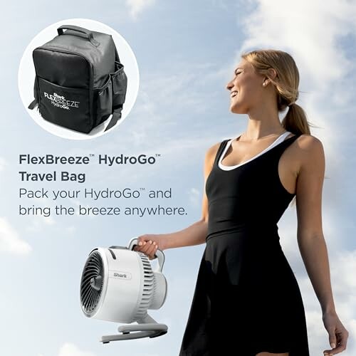 Woman with portable fan and travel bag outdoors.